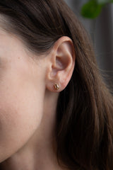 Close-up of a woman’s ear wearing Tura Sugden Hexagonal Diamond Earrings in recycled 18k gold.