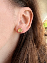 Close-up of an ear wearing Tura Sugden Diamond Slice Earrings and a gold hoop.